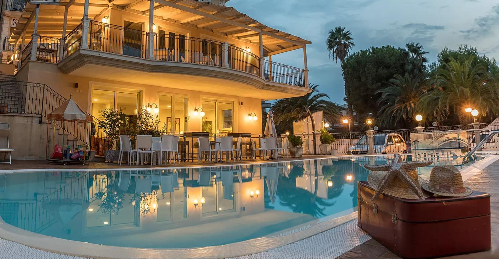Villa elegante con piscina, palme e atmosfera serale accogliente.