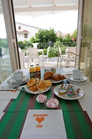 Colazione con croissant, succhi e dolci su tavolo all'aperto.