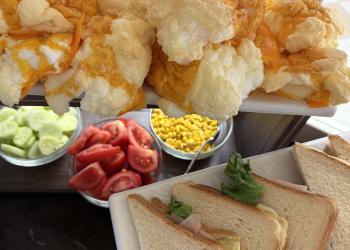 Un buffet colorato con formaggio, verdure fresche e panini invitanti.