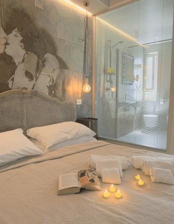 Camera da letto elegante con decorazione murale, candele e bagno moderno a vista.