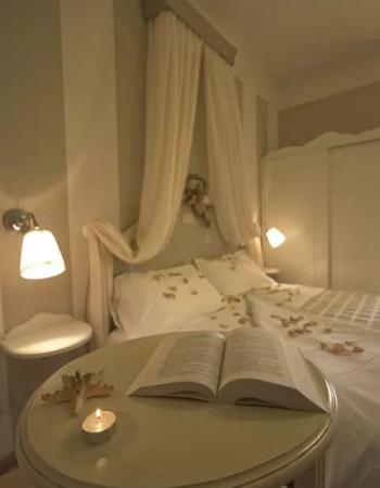 Camera da letto accogliente con letto a baldacchino, libro e candela accesa.