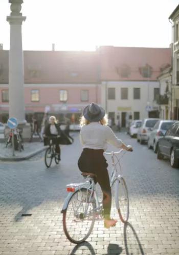 Persona in bicicletta su strada acciottolata, con luce solare di sfondo.