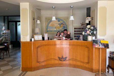 Cozy hotel reception, smiling family behind wooden counter.