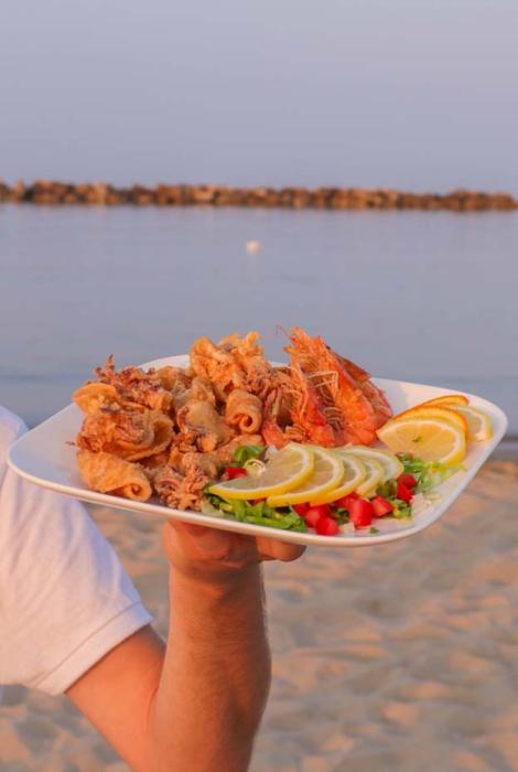 Piatto di fritto misto di mare al tramonto sulla spiaggia, fresco e invitante.
