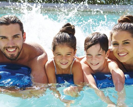 Famiglia felice in piscina, sorridono e si divertono insieme sull'acqua.