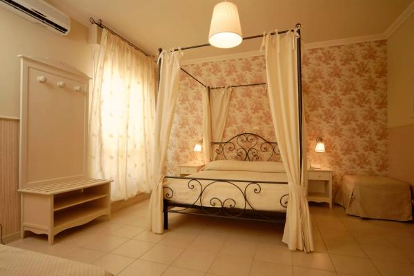 Camera con letto a baldacchino, pareti floreali e illuminazione soffusa.