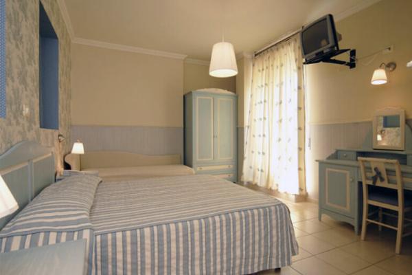 Camera da letto con arredi azzurri, due letti e TV a parete.