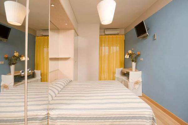 Camera da letto moderna con pareti blu, tende gialle, TV e specchio grande.