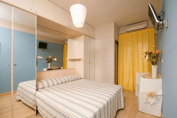 Camera da letto moderna con pareti blu, tende gialle e specchi.