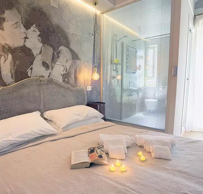 Camera da letto romantica con candele, libro aperto e bagno a vista.