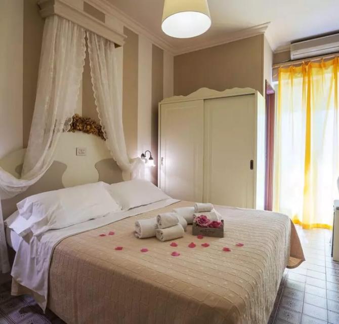 Camera elegante con letto matrimoniale, tende gialle e decorazioni romantiche.