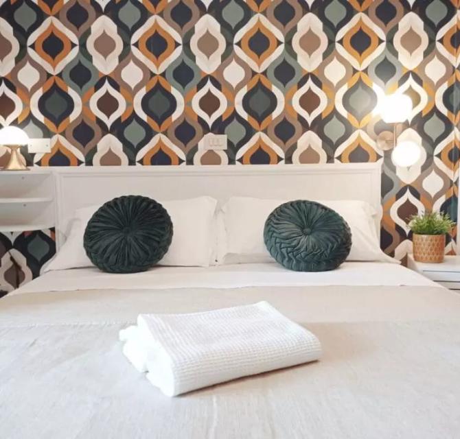 Camera da letto con cuscini verdi e carta da parati geometrica.