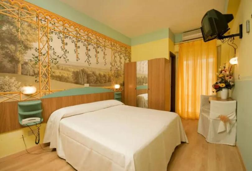 Camera accogliente con letto matrimoniale, decorazioni floreali e TV a parete.