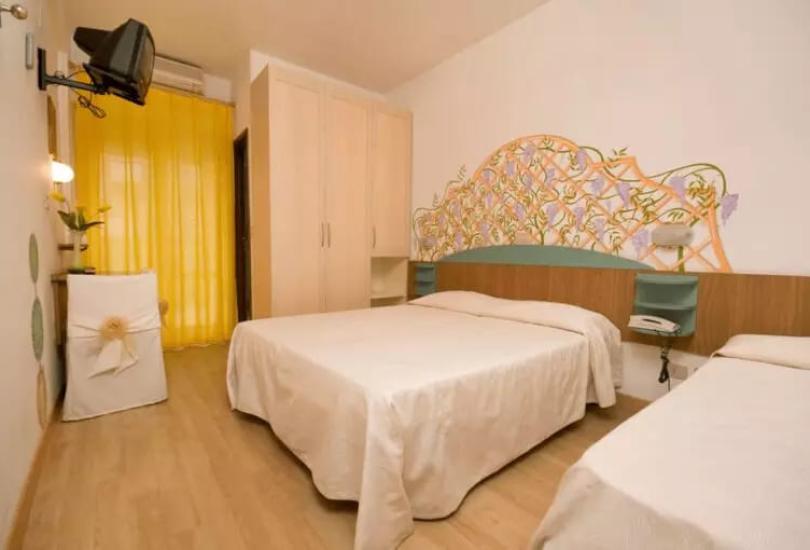 Camera semplice con letto matrimoniale e decorazione colorata sulla parete.