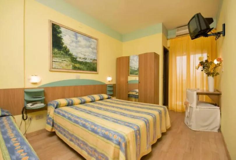 Camera da letto con letto matrimoniale, TV e tendaggi gialli.
