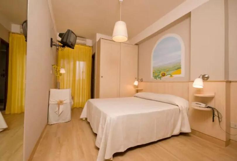 Camera accogliente con letto matrimoniale, arredi chiari e decorazioni semplici.