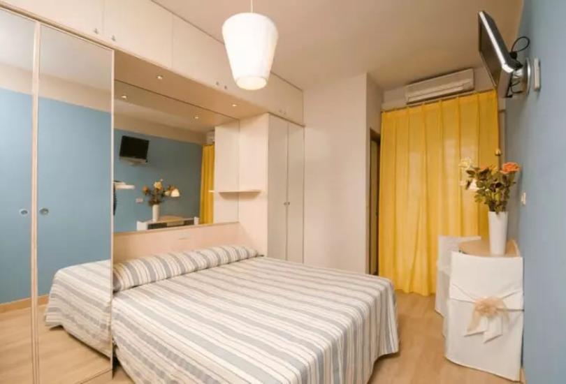 Camera da letto moderna con letto matrimoniale, specchi e tende gialle.
