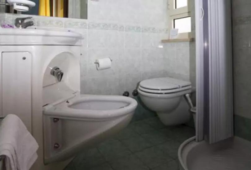 Bagno compatto con lavabo, bidet, WC e doccia, piastrelle verdi e bianche.