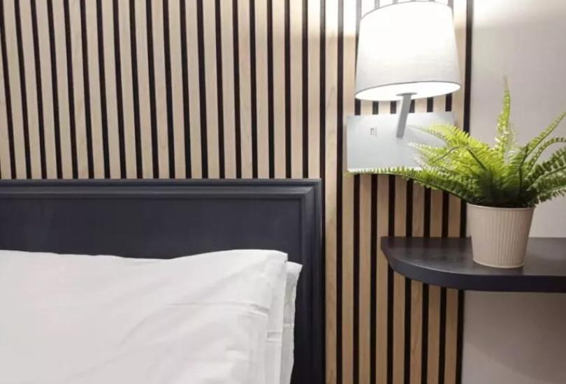 Camera da letto moderna con lampada, pianta e parete a righe.