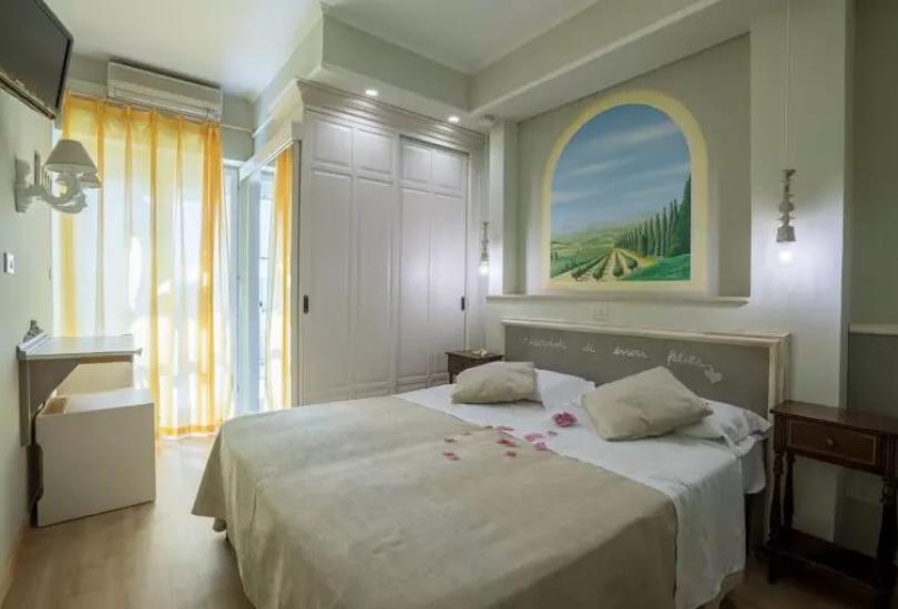 Camera accogliente con letto matrimoniale e dipinto murale paesaggistico.